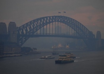 Commuter ferries sail past the Sydney Harbour Bridge as smoke haze from bushfires in New South Wales blankets the CBD in Sydney, Monday, December 2, 2019. (AAP Image/Steven Saphore) NO ARCHIVING