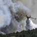 A Canadair firefighting plane sprays water during a fire in Dervenochoria, north-west of Athens, on July 19, 2023. Extreme heat was forecast across the globe on July 19, 2023, as wildfires raged and health warnings were in place in parts of Asia, Europe and North America. Firefighters battled blazes in parts of Greece and the Canary Islands, while Spain issued heat alerts and some children in Italy's Sardinia were told to stay away from sports. (Photo by SPYROS BAKALIS / AFP)