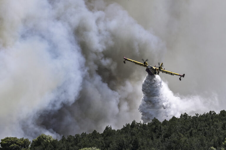 A Canadair firefighting plane sprays water during a fire in Dervenochoria, north-west of Athens, on July 19, 2023. Extreme heat was forecast across the globe on July 19, 2023, as wildfires raged and health warnings were in place in parts of Asia, Europe and North America. Firefighters battled blazes in parts of Greece and the Canary Islands, while Spain issued heat alerts and some children in Italy's Sardinia were told to stay away from sports. (Photo by SPYROS BAKALIS / AFP)