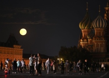 The August Super Blue Moon sets behind a historical building and the St. Basil's Cathedral, right, as people walk in Red Square in Moscow, Russia, Wednesday, Aug. 30, 2023. The cosmic curtain rises Wednesday night with the second full moon of the month, the reason it is considered blue. It is dubbed a supermoon because it is closer to Earth than usual, appearing especially big and bright. (AP Photo/Alexander Zemlianichenko)