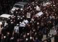 Mourners carry the coffins and pictures of people killed in a rocket strike from Lebanon a day earlier, during a mass funeral in the Druze town of Majdal Shams in the Israel-annexed Golan Heights, on July 28, 2024. The Israeli military said the victims were struck by an Iranian-made rocket carrying a 50-kilogram warhead that was fired by Lebanese Hezbollah group at a soccer field in the Druze Arab town. Hezbollah has denied responsibility for the strike. (Photo by Menahem KAHANA / AFP)