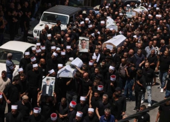 Mourners carry the coffins and pictures of people killed in a rocket strike from Lebanon a day earlier, during a mass funeral in the Druze town of Majdal Shams in the Israel-annexed Golan Heights, on July 28, 2024. The Israeli military said the victims were struck by an Iranian-made rocket carrying a 50-kilogram warhead that was fired by Lebanese Hezbollah group at a soccer field in the Druze Arab town. Hezbollah has denied responsibility for the strike. (Photo by Menahem KAHANA / AFP)